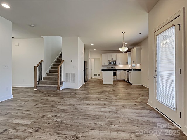 231 Brook Ave SE, Concord, NC 28025 - kitchen featuring open floor plan, appliances with stainless steel finishes, dark countertops, wood finished floors, and recessed lighting