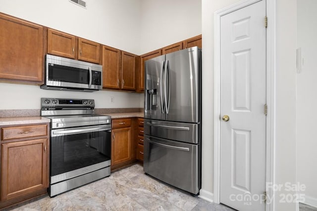 4714 Adamshire Ave, Concord, NC 28025 - kitchen with stainless steel appliances, brown cabinets, light countertops, and baseboards