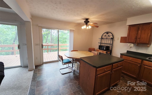 253 Nors Way Unit 26, Lake Lure, NC 28746 - kitchen with dark countertops, a ceiling fan, a textured ceiling, a kitchen island, and baseboards