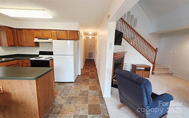 253 Nors Way Unit 26, Lake Lure, NC 28746 - kitchen with white appliances, under cabinet range hood, dark countertops, stone finish flooring, and brown cabinets