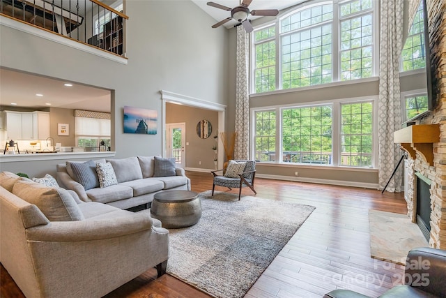 1868 Chestnut Hill Dr, Tega Cay, SC 29708 - living area with a towering ceiling, a stone fireplace, a ceiling fan, wood finished floors, and baseboards