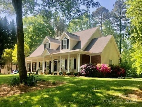 390 Robinson Rd, Mooresville, NC 28117 - view of front facade featuring a front yard, covered porch, and view of wooded area