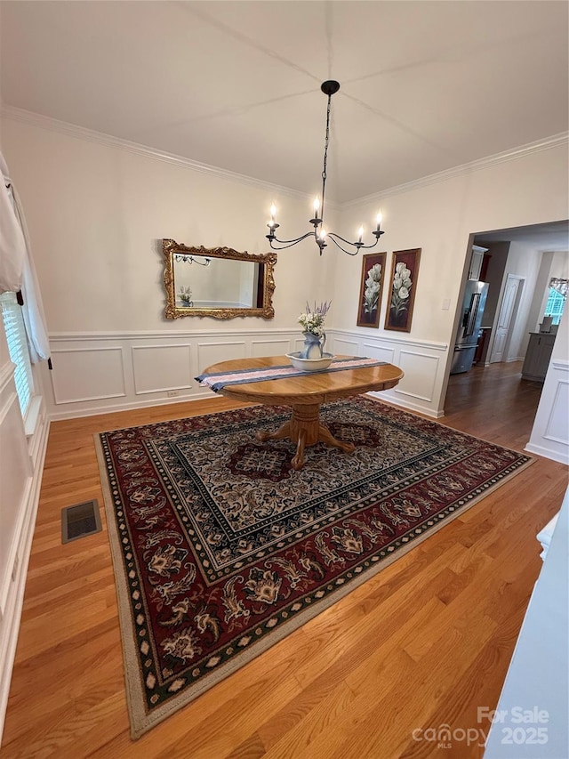 390 Robinson Rd, Mooresville, NC 28117 - dining room featuring ornamental molding, a chandelier, wood finished floors, a wainscoted wall, and a decorative wall