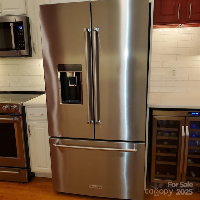 390 Robinson Rd, Mooresville, NC 28117 - kitchen featuring stainless steel appliances, wine cooler, tasteful backsplash, wood finished floors, and white cabinetry