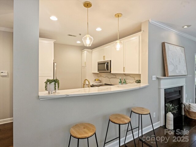 416 Queens Rd Unit 10, Charlotte, NC 28207 - kitchen with stainless steel microwave, ornamental molding, baseboards, backsplash, and a kitchen breakfast bar