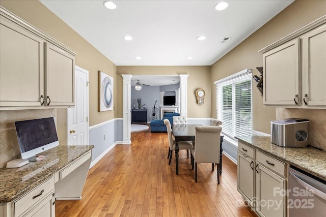 13528 Philip Michael Rd, Huntersville, NC 28078 - kitchen featuring a glass covered fireplace, stainless steel dishwasher, light wood-type flooring, decorative columns, and tasteful backsplash