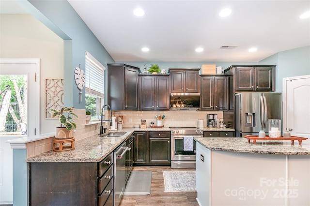 5092 Nighthawk Dr, Indian Land, SC 29707 - kitchen featuring appliances with stainless steel finishes, a sink, light wood-style floors, dark brown cabinets, and light stone countertops