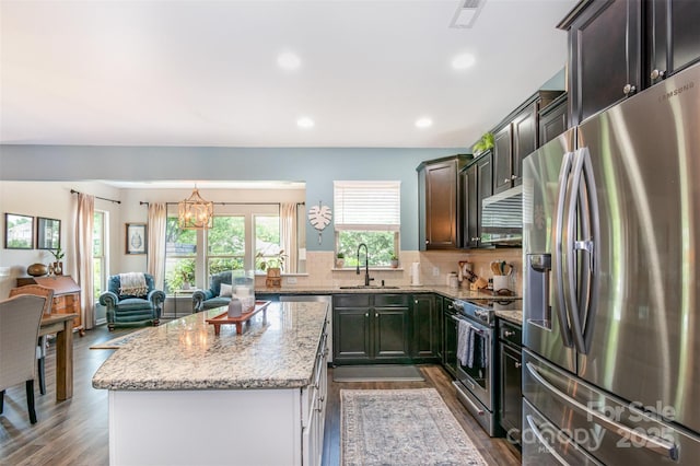5092 Nighthawk Dr, Indian Land, SC 29707 - kitchen featuring appliances with stainless steel finishes, a center island, a sink, light stone countertops, and a chandelier