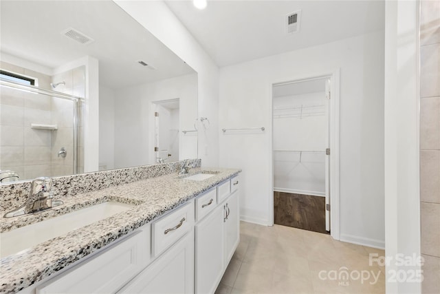 15208 Caspian Way, Charlotte, NC 28278 - bathroom featuring double vanity, a shower stall, a walk in closet, baseboards, and tile patterned flooring