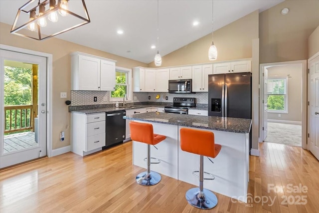 39 Curtis Miles Rd, Alexander, NC 28701 - kitchen featuring stainless steel appliances, white cabinetry, tasteful backsplash, light wood finished floors, and vaulted ceiling