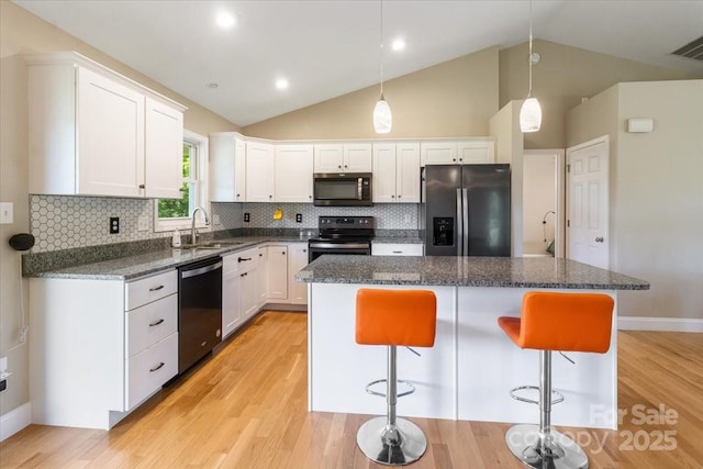 39 Curtis Miles Rd, Alexander, NC 28701 - kitchen with appliances with stainless steel finishes, a sink, vaulted ceiling, a kitchen island, and white cabinetry