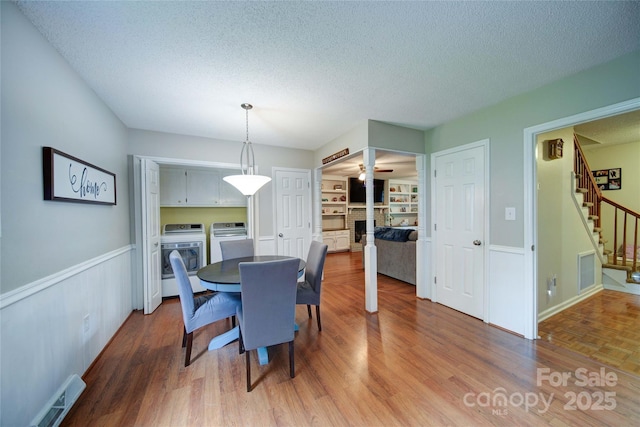 734 Forestbrook Dr, Gastonia, NC 28056 - dining space with washer and clothes dryer, a textured ceiling, stairs, a fireplace with raised hearth, and wood finished floors