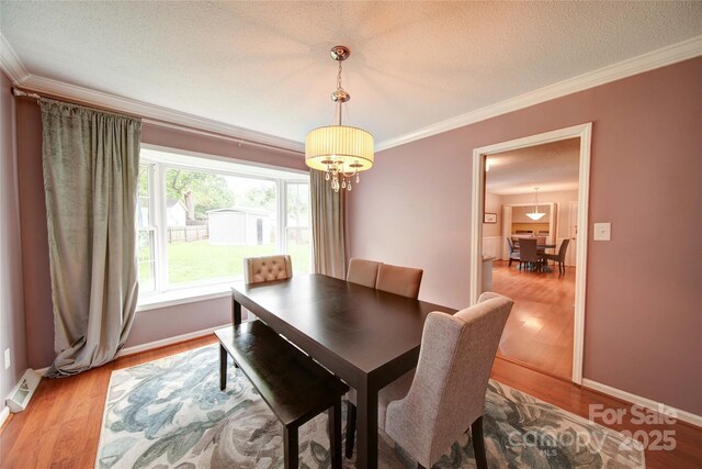 734 Forestbrook Dr, Gastonia, NC 28056 - dining space with ornamental molding, a chandelier, light wood-style floors, and a textured ceiling