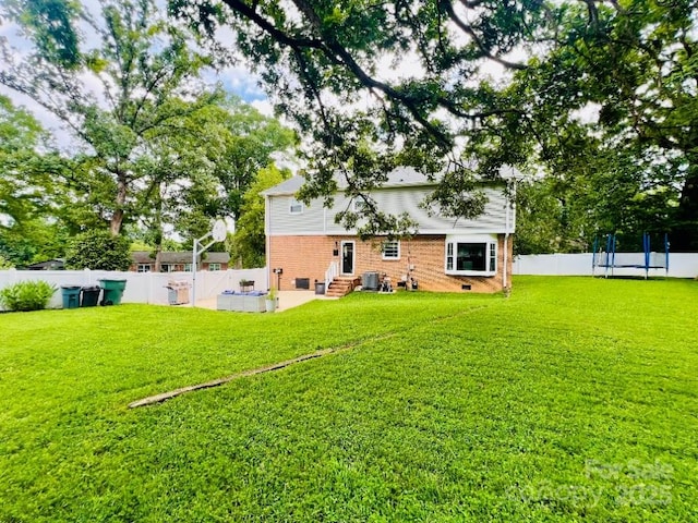 734 Forestbrook Dr, Gastonia, NC 28056 - rear view of property with entry steps, a trampoline, a fenced backyard, and brick siding