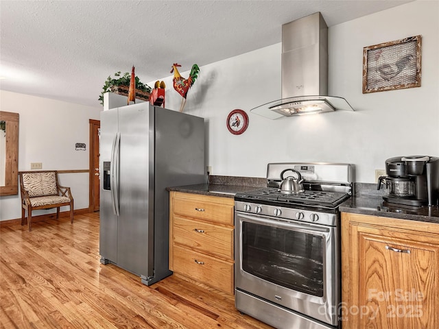 505 Middle Top Loop, Maggie Valley, NC 28751 - kitchen featuring appliances with stainless steel finishes, wall chimney range hood, dark countertops, light wood-style flooring, and a textured ceiling