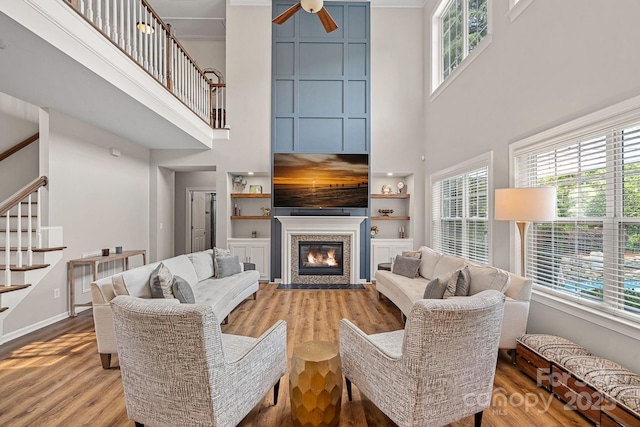 1849 Still Water Ln, Indian Land, SC 29707 - living room featuring a towering ceiling, ceiling fan, stairs, light wood-style floors, and built in features