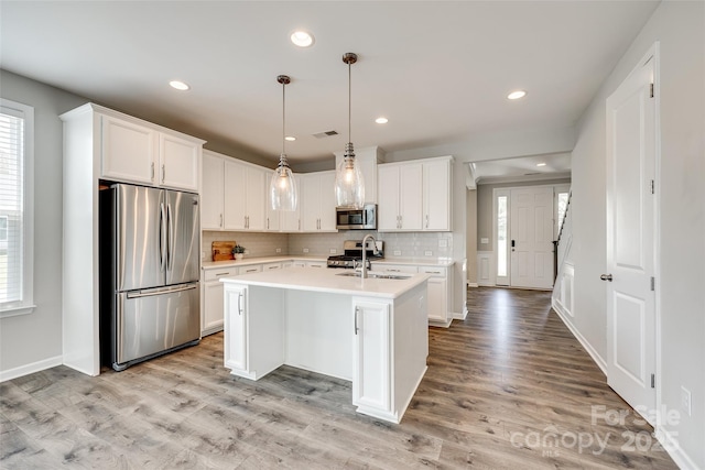 173 Morgans Branch Rd, Belmont, NC 28012 - kitchen with stainless steel appliances, a sink, light countertops, decorative backsplash, and a center island with sink