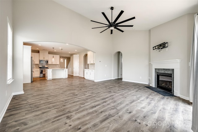 173 Morgans Branch Rd, Belmont, NC 28012 - unfurnished living room with high vaulted ceiling, a ceiling fan, baseboards, a premium fireplace, and wood finished floors