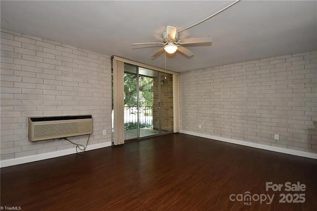 1807 S Hawthorne Rd, Winston Salem, NC 27103 - unfurnished living room featuring baseboards, a wall unit AC, brick wall, a ceiling fan, and wood finished floors