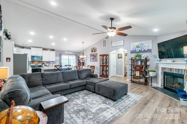2737 Bobcat Rd, Heath Springs, SC 29058 - living area featuring ceiling fan, a fireplace, light wood-type flooring, arched walkways, and vaulted ceiling