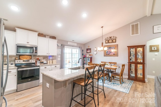2737 Bobcat Rd, Heath Springs, SC 29058 - kitchen featuring appliances with stainless steel finishes, a sink, lofted ceiling, light wood finished floors, and white cabinetry