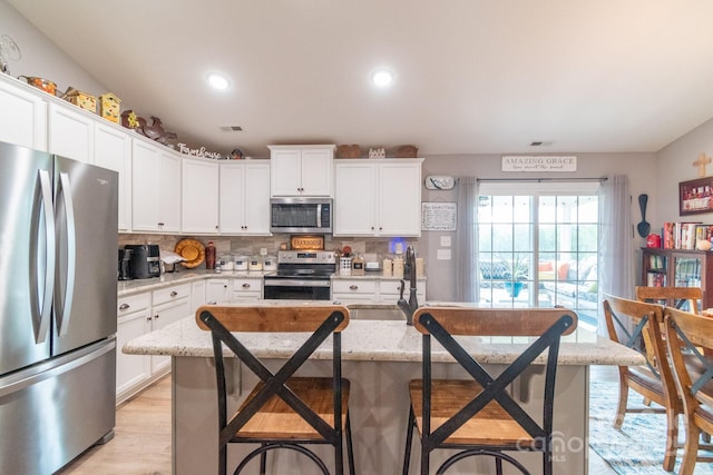 2737 Bobcat Rd, Heath Springs, SC 29058 - kitchen featuring appliances with stainless steel finishes, a sink, a kitchen breakfast bar, tasteful backsplash, and white cabinetry