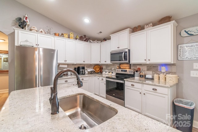 2737 Bobcat Rd, Heath Springs, SC 29058 - kitchen with stainless steel appliances, a sink, white cabinets, decorative backsplash, and light stone counters