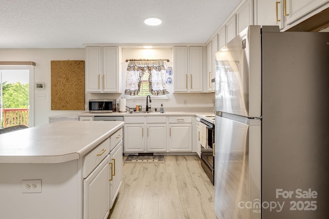 101 Michael Ct, Leicester, NC 28748 - kitchen with stainless steel appliances, a sink, light wood-type flooring, light countertops, and a textured ceiling