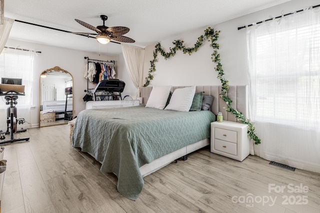 101 Michael Ct, Leicester, NC 28748 - bedroom with light wood-style flooring, a textured ceiling, a ceiling fan, and arched walkways