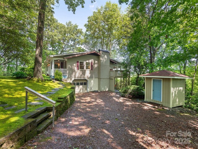 573 Valeria Ln, Pisgah Forest, NC 28768 - view of front of property with dirt driveway, an attached garage, a front lawn, and a chimney