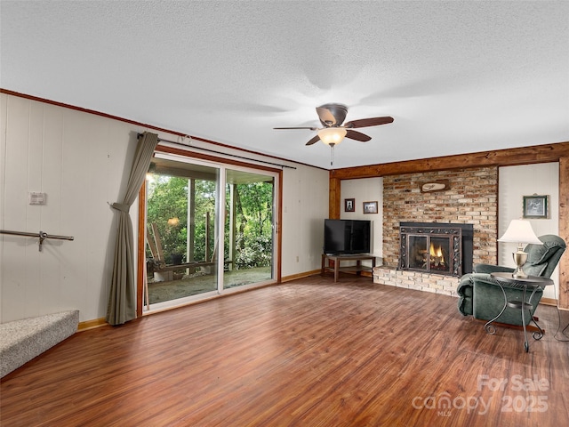 573 Valeria Ln, Pisgah Forest, NC 28768 - unfurnished living room with wood finished floors, a ceiling fan, a fireplace, and a textured ceiling