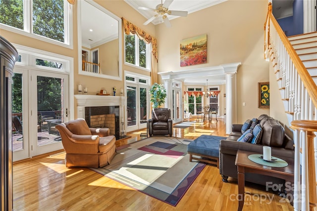 4740 Myers Ln, Harrisburg, NC 28075 - living room featuring decorative columns, a high ceiling, ornamental molding, a fireplace with raised hearth, and light wood finished floors