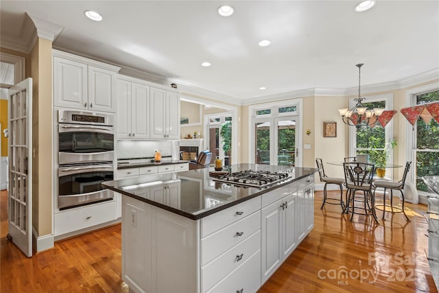 4740 Myers Ln, Harrisburg, NC 28075 - kitchen featuring stainless steel appliances, ornamental molding, white cabinetry, light wood-style flooring, and a center island