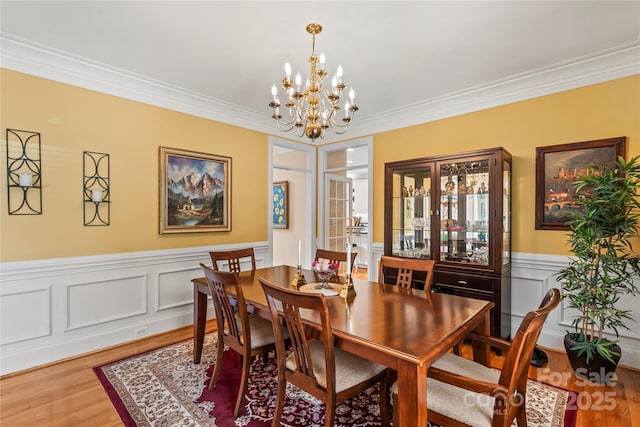 4740 Myers Ln, Harrisburg, NC 28075 - dining room featuring a chandelier, ornamental molding, light wood-style flooring, wainscoting, and a decorative wall