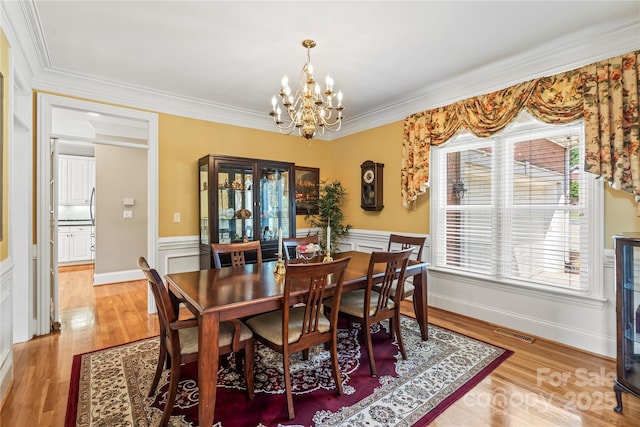 4740 Myers Ln, Harrisburg, NC 28075 - dining room with a chandelier, ornamental molding, wainscoting, and light wood finished floors