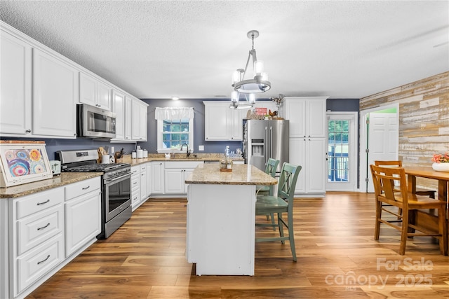 106 Laren Rd, Shelby, NC 28152 - kitchen featuring stainless steel appliances, a breakfast bar area, a chandelier, white cabinets, and a textured ceiling