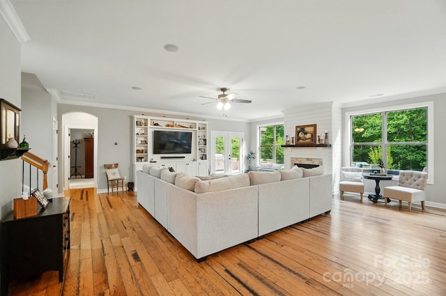 110 St Sophia Ct, Mooresville, NC 28117 - living area with arched walkways, a ceiling fan, ornamental molding, light wood-style floors, and healthy amount of natural light