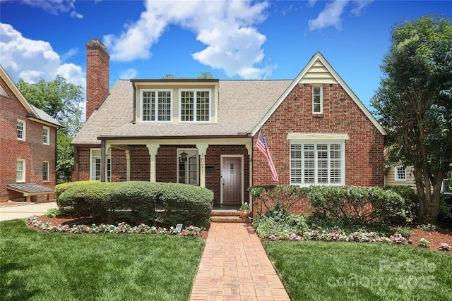 1021 Isleworth Ave, Charlotte, NC 28203 - tudor house with a front lawn, a shingled roof, brick siding, and a chimney