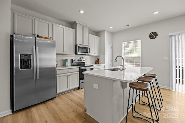 3108 Beeler Ln, Charlotte, NC 28208 - kitchen featuring stainless steel appliances, a sink, light wood-style flooring, a center island with sink, and tasteful backsplash