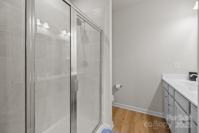 3108 Beeler Ln, Charlotte, NC 28208 - bathroom featuring vanity, a stall shower, wood finished floors, toilet, and baseboards