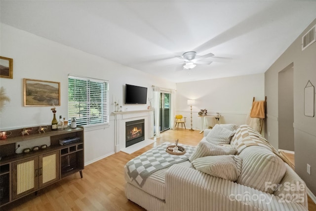 3737 Winding Creek Ln, Charlotte, NC 28226 - living room featuring healthy amount of natural light, light wood-style floors, a ceiling fan, and a warm lit fireplace