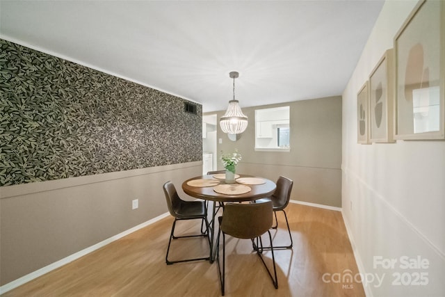3737 Winding Creek Ln, Charlotte, NC 28226 - dining space featuring light wood-style floors, wallpapered walls, a chandelier, baseboards, and wainscoting
