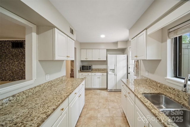 3737 Winding Creek Ln, Charlotte, NC 28226 - kitchen featuring white refrigerator with ice dispenser, stainless steel microwave, a sink, white cabinetry, and light stone countertops