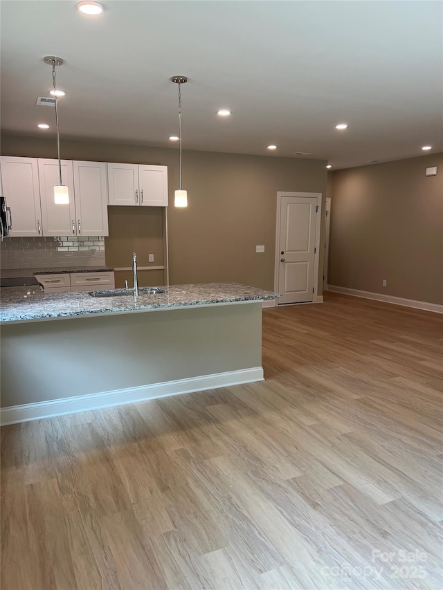 210 Johnson St, Troutman, NC 28116 - kitchen with a sink, recessed lighting, light wood-style flooring, light stone countertops, and baseboards
