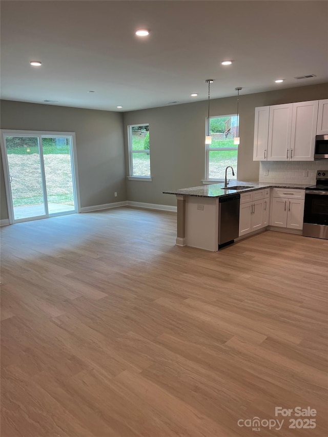 210 Johnson St, Troutman, NC 28116 - kitchen with stainless steel appliances, a sink, open floor plan, white cabinetry, and light wood-type flooring