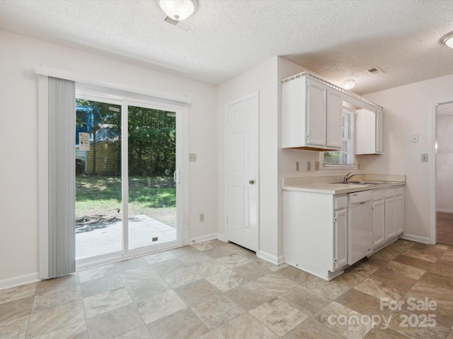 3313 Fortis Ln, Matthews, NC 28105 - kitchen featuring white dishwasher, light countertops, white cabinetry, a textured ceiling, and baseboards