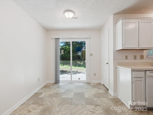 3313 Fortis Ln, Matthews, NC 28105 - unfurnished dining area featuring a textured ceiling, baseboards, and light stone finish floors
