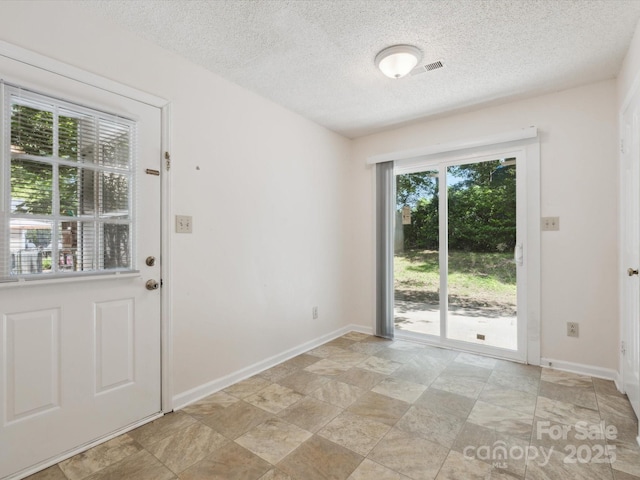 3313 Fortis Ln, Matthews, NC 28105 - entryway with stone finish floors, a textured ceiling, and baseboards