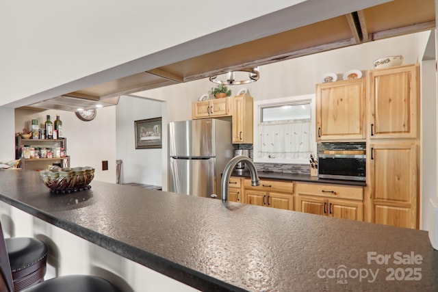 44 Falls Creek Rd, Pisgah Forest, NC 28768 - kitchen featuring freestanding refrigerator, a kitchen breakfast bar, dark countertops, light brown cabinetry, and oven