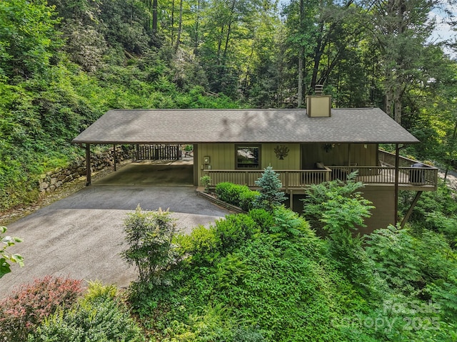 44 Falls Creek Rd, Pisgah Forest, NC 28768 - rustic home with a chimney, asphalt driveway, roof with shingles, a view of trees, and an attached carport